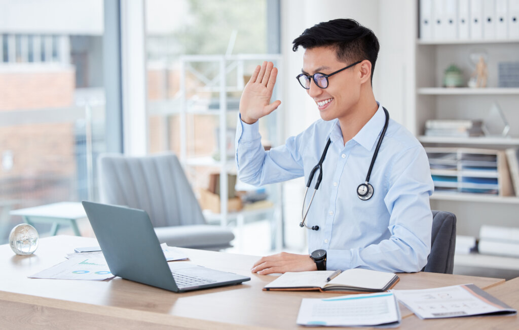 Medical, video call and telehealth with an asian man doctor in his office at the hospital for remote consulting. Healthcare, virtual and wave with a young male medicine professional working online.