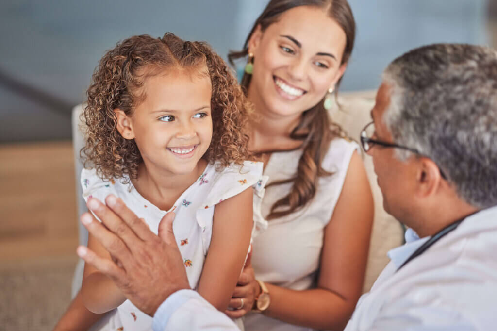 Doctor interacting with a smiling young girl and her mother during a visit